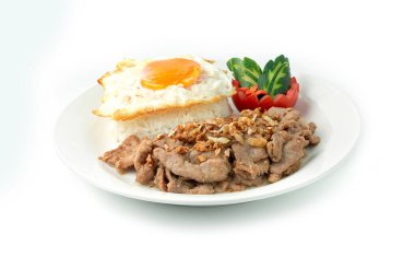 Tayland yemeği sarımsaklı ve Tayland biberli kızarmış sarımsaklı pilav, kızarmış yumurta ve domates salatalıklı arka planda izole edilmiş beyaz tabak.