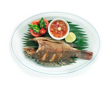 Kızarmış Balık (Tilapia) Acılı Baharatlı Tayland Sosu Baharatlı Baharatlı Baharat Sosu oyulmuş salatalık, acı biber ve domates sosuyla servis edilir.