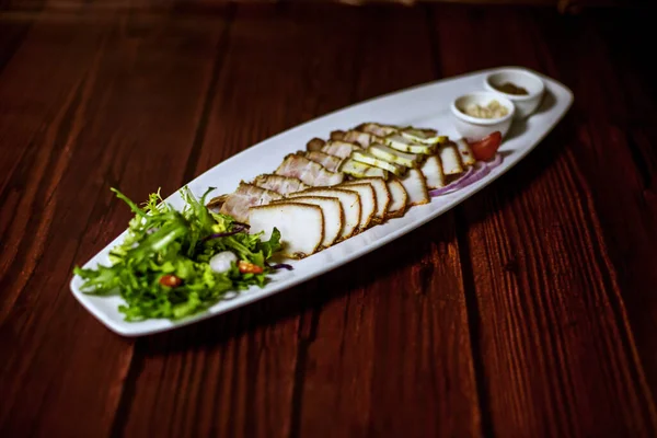 Beyaz bir tabakta otlu ve soslu lezzetli tuzlu domuz yağı.