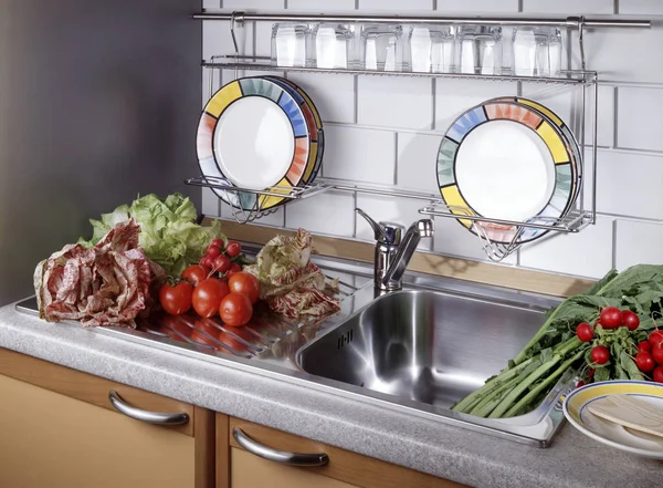 Kitchen sink with dishes and vegetables