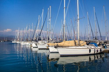 Türkiye 'nin Mugla ilinin Fethiye ilçesinde liman tekneleri güneşli bir yaz günü turkuaz denizde gemi direkleri ve yansımaları oluşturuyor. Tatil, Akdeniz ve Ege 'nin en iyi turistik beldesidir..