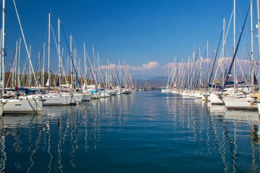Türkiye 'nin Mugla ilinin Fethiye ilçesinde liman tekneleri güneşli bir yaz günü turkuaz denizde gemi direkleri ve yansımaları oluşturuyor. Tatil, Akdeniz ve Ege 'nin en iyi turistik beldesidir..