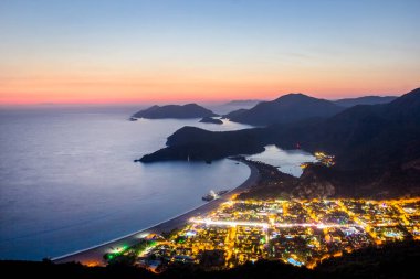 Oludeniz, Türkiye 'de güzel bir gün batımı olan Blue Lagoon' un muhteşem hava manzarası. Plajlı ve dağlı yaz manzarası, yeşil orman, gök mavisi su, kumlu sahil ve açık güneşli bir günde mavi gökyüzü en iyi turist.