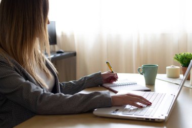 Genç iş kadını telesekreteri masa başında oturuyor kağıtları yazıyor ve bilgisayarında ev ofisinde daktilo yazıyor. Uzaklaştırma.