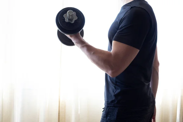 Side profile view photo of sportive strong muscular guy building muscles on arms by lifting dumbbells, isolated on bright background.