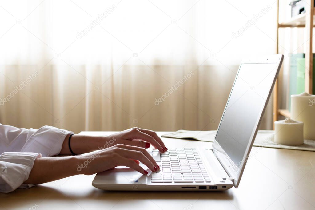 Businesswoman typing on laptop at workplace from home. Woman teleworking on manual keyboard in home office.