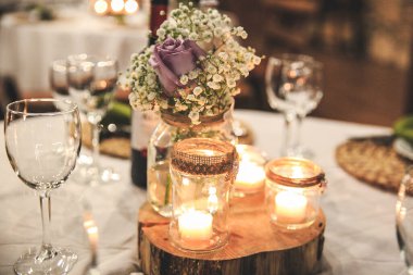 Çiçekler ve mumlarla süslenmiş düğün masası.