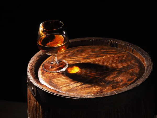 Glass of cognac with barrel on wooden backgroun — Stock Photo, Image