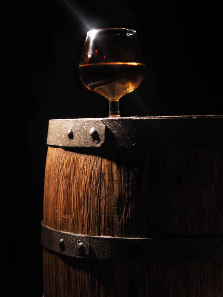 Glass of cognac with barrel on wooden backgroun — Stock Photo, Image