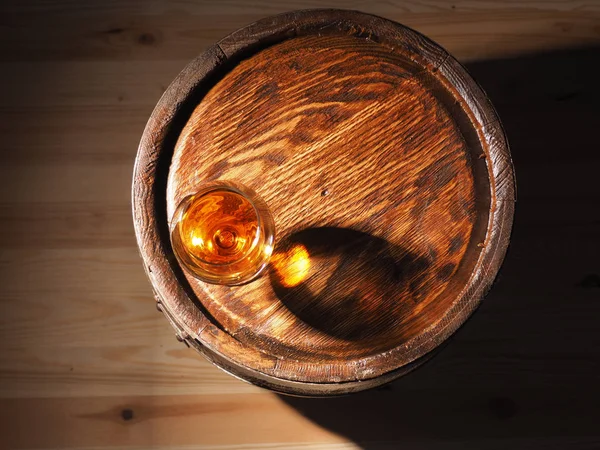 Glas cognac met vat op houten pagina — Stockfoto