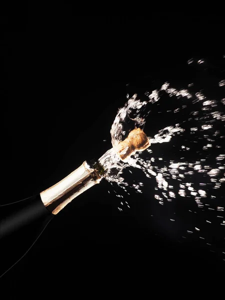 Garrafa de champanhe e spray em backgroun preto — Fotografia de Stock