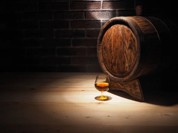 Glas cognac met vat op houten tafel — Stockfoto