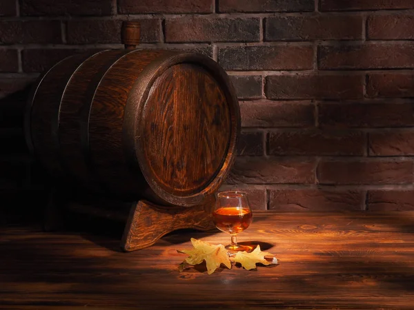 Glass of cognac with barrel on wooden table — Stock Photo, Image