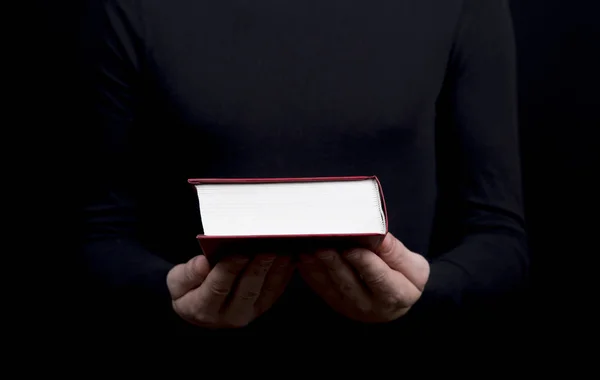 A man dressed in black holding a book in a red cover — Stock Photo, Image