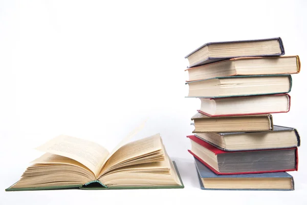 Open book in hardcover on a table next to an uneven stack of boo — Stock Photo, Image