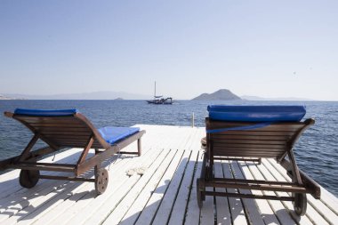 İki beyaz ahşap sandalye ahşap bir iskele ile deniz agains üzerinde