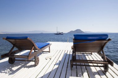 İki beyaz ahşap şezlong şezlong deniz agai tarafından ahşap bir iskele üzerinde