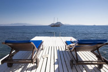 B karşı deniz kenarında beyaz bir rıhtımda iki ahşap sandalye