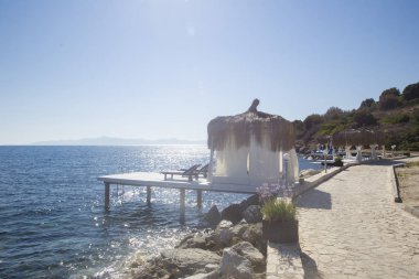 Bir kaç beyaz bungalows bir bambu çatısı ve küçük bir iskele ile bir