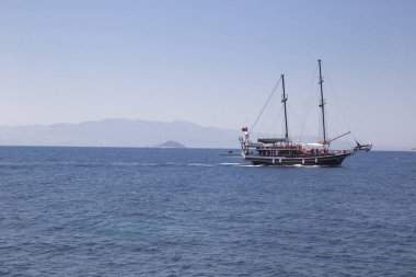 Bir bulut karşı deniz kenarında turist ile güzel bir yat yelken