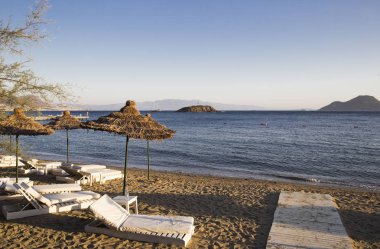düzensizce bulunduğu beyaz plaj şezlong beach bambo altında