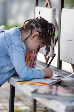 pigtails içinde mavi bir ceket ve dört yaşındaki kızla benc üzerinde çizer