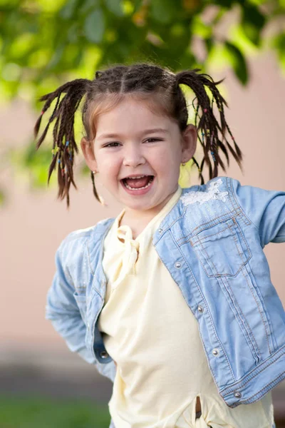Skrattande fyra-årig tjej med en fläta frisyr i en jacka en — Stockfoto
