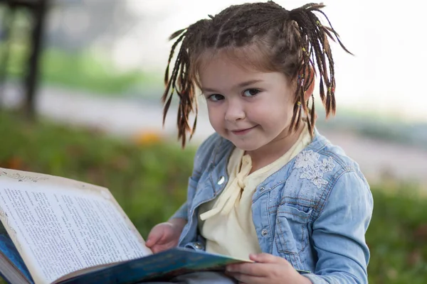 Beautiful little girl with pigtails in a blue jacket looking at — Stock Photo, Image