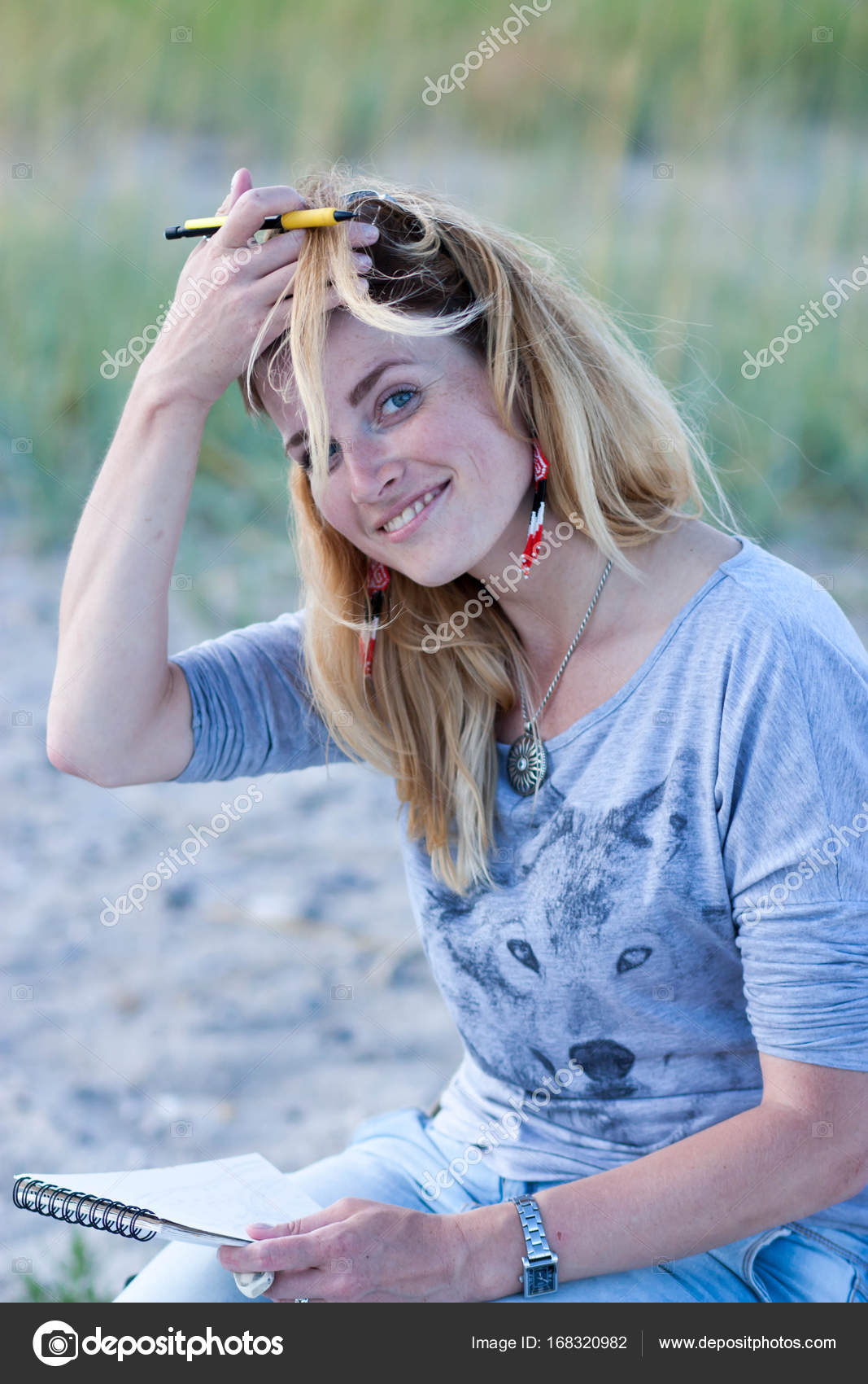 Young girl with a notepad and pencil throws back her hair from t