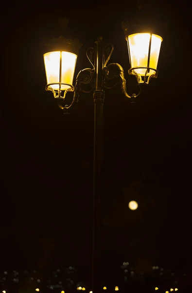 A lit forged street lamp with two lamps on a black background of — Stock Photo, Image
