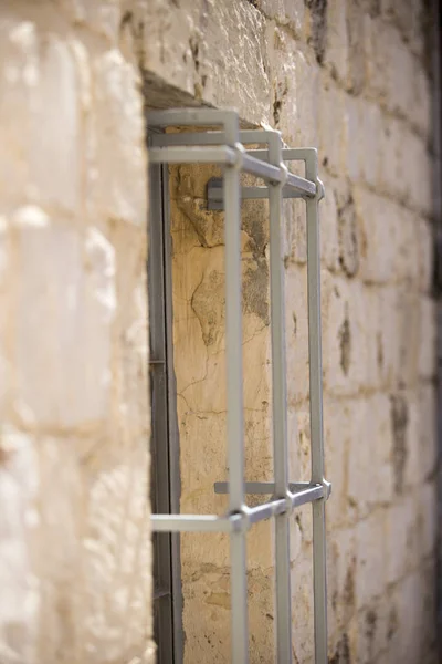 Part of an ancient stone wall of light brown light with  iron gr — Stock Photo, Image