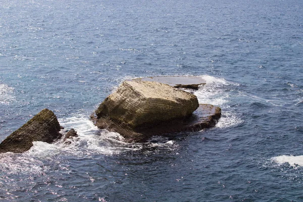 Pequeñas olas espumosas del mar del desierto golpean una roca solitaria — Foto de Stock