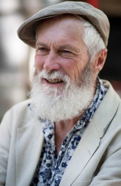 güzel bir güçlü iradeli bronzlaşmış yüz ve bir ışık kap, mavi gömlek ve ceket sokak arka plan bulanık beyaz sakalı ile etkileyici bir gri saçlı yaşlı adamın duygu profilinde