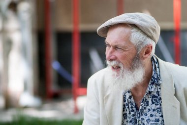 duyguları ifade bir gri saçlı yaşlı adamın güzel bir güçlü iradeli bronzlaşmış yüz ve bir ışık kap, mavi gömlek ve ceket sokak arka plan bulanık beyaz sakalı ile
