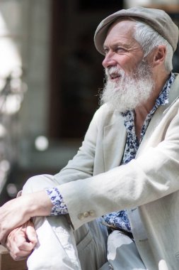 duyguları ifade bir gri saçlı yaşlı adamın güzel bir güçlü iradeli bronzlaşmış yüz ve bir ışık kap, mavi gömlek ve ceket sokak arka plan bulanık beyaz sakalı ile