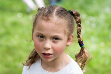 güzel bir anlatım beş yaşındaki kızın iri yeşil gözleri ve yeşil alan Park bulanık bir arka plan üzerinde komik bezleri şeklinde bir saç kesimi ile duygular