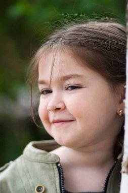 güzel bir park ve yeşil renk arka plan bulanık üzerinde komik bezleri şeklinde bir saç kesimi ve beş yaşındaki kızla ifade duyguların