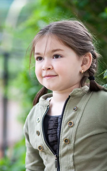 緑と公園の色の背景をぼかした写真に面白いハーネスの形で散髪を持つ美しい表情豊かな 歳女の子の感情 — ストック写真
