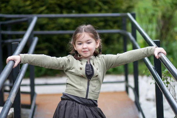 一个美丽表现力的五岁女孩的情绪 在一个模糊的背景下的绿色和公园颜色的滑稽辫子的形式的发型 — 图库照片