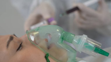 Bir kadın hasta koronavirüs enfeksiyonu geçirdiği için solunum ve oksijen alır. Bir doktor arka planda pozitif test tüpü gösteriyor..