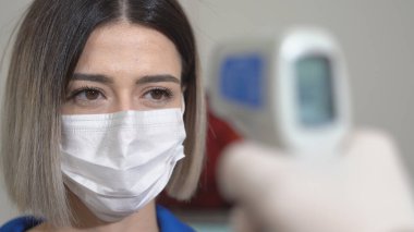 Coronavirüs enfeksiyonunu bulmak için termometreyle kadın ateşini ölçmek, Covid-19. Yakın çekim..