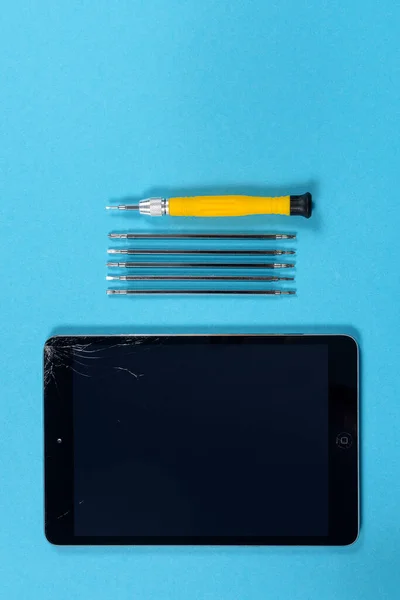 Tablet repair concept. Broken tablet and mini screwdriver