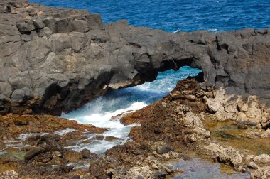 Kıyıdaki kaya kemeri ve denizin dalgaları Charco del Palo Lanzarote 'a çarpıyor.