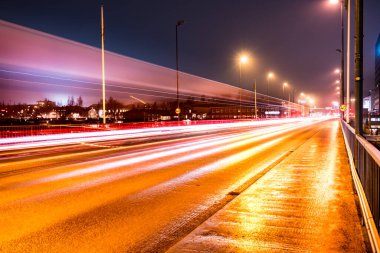 Umea şehrinin merkez köprüsündeki yoğun gece trafiğinden renkli ışık izleri, sisli sonbahar havası, İsveç