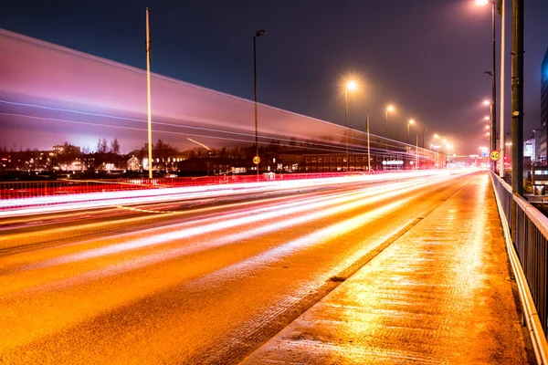 colorful light traces from busy night traffic on the central bridge in Umea city, foggy autumn weather, Sweden