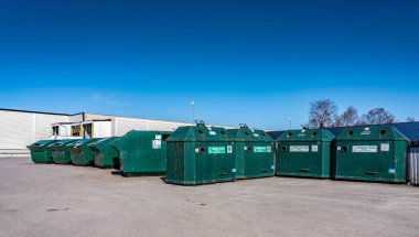 Park yerindeki büyük umumi geri dönüşüm istasyonu farklı ev atıklarını atmak için - plastik, metal, kağıt, karton. Kuzey İsveç, Umea. Güneşli bir gün. Yeşil metal kaplar sıralanmış geri dönüşüm