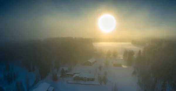 Majestic view of winter sunset with very large sun spot in frozen foggy air, winter pine tree forest, aerial, Grano village, around Umea city, Northern Sweden, short winter day, subarctic landscape.
