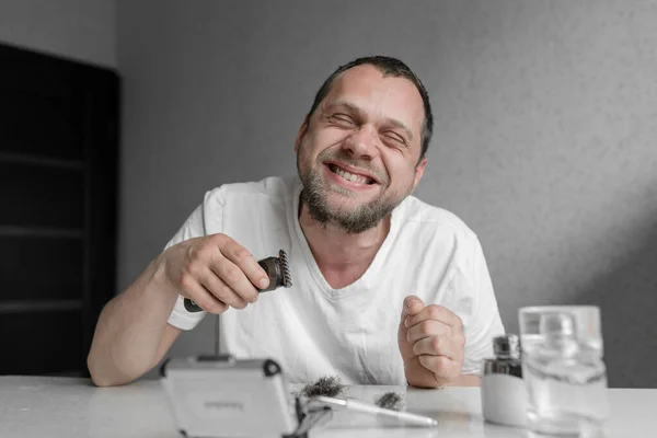 guy shaves beard in isolation. the guy with the smile broet beard. home made shave. shaver for beards. haircut for isolation. haircut for quarantine