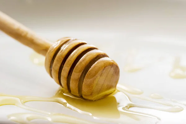 Honey drips from a wooden spoon isolated on a white background