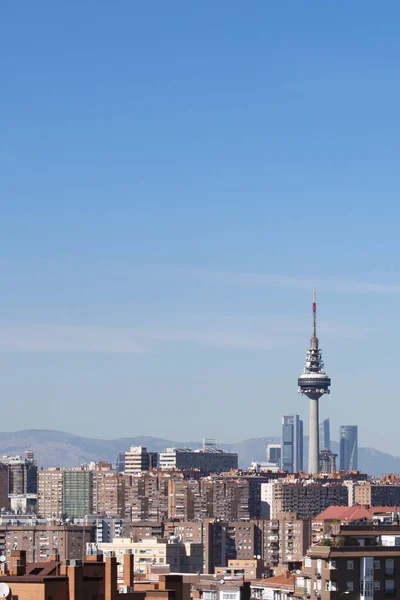 Madrid şehrini dikey bir çerçevede görmek binaların çatılarını ve torrespaa, arka planda dağlar ve mavi gökyüzü vardır..